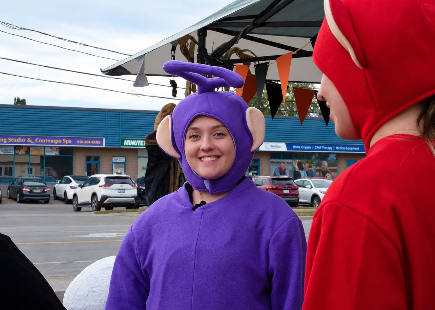 A smiling guest in a purple character costume chats beside a red-costumed guest.