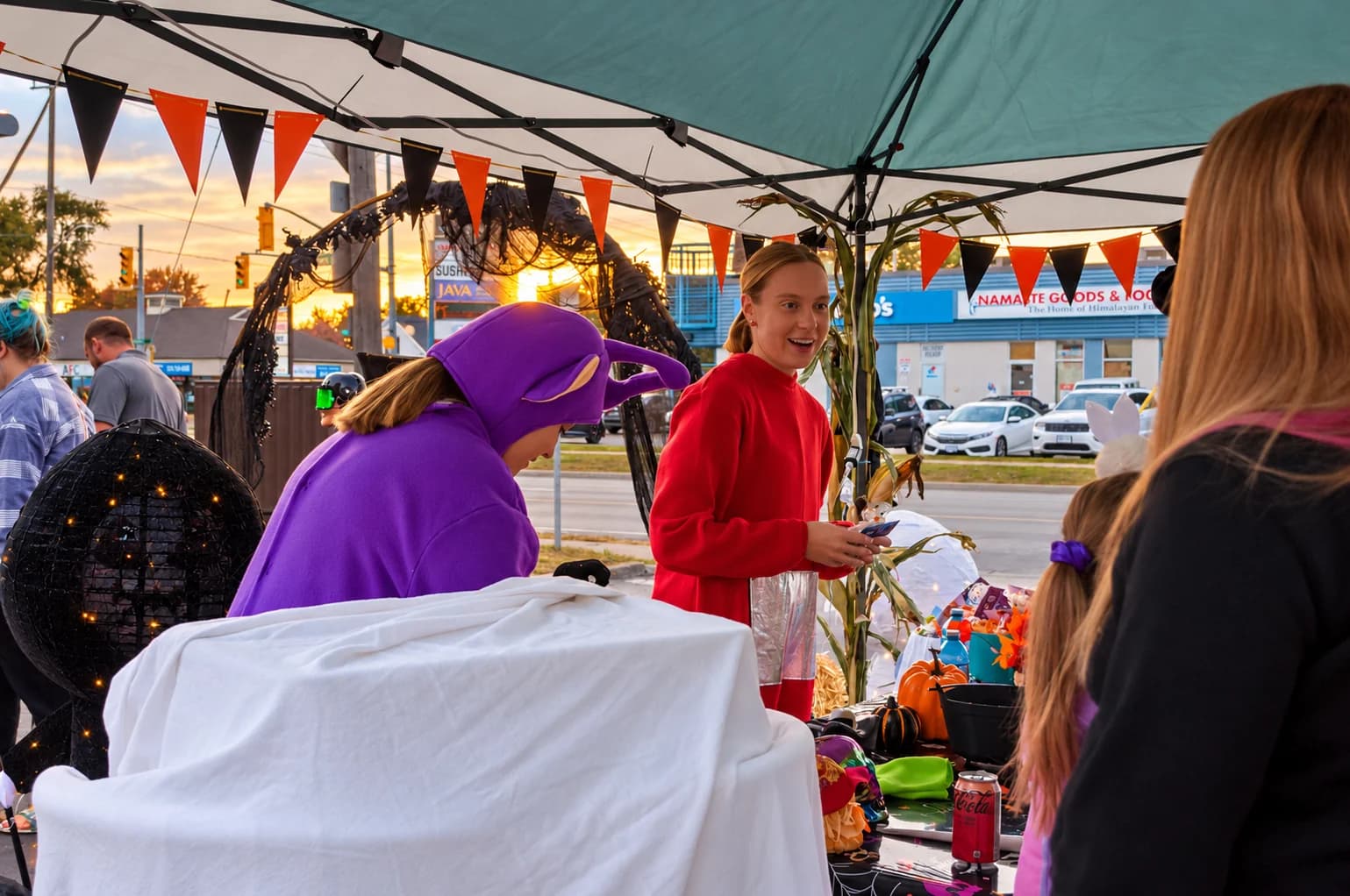 Costumed hosts greet a guest as the sun sets.